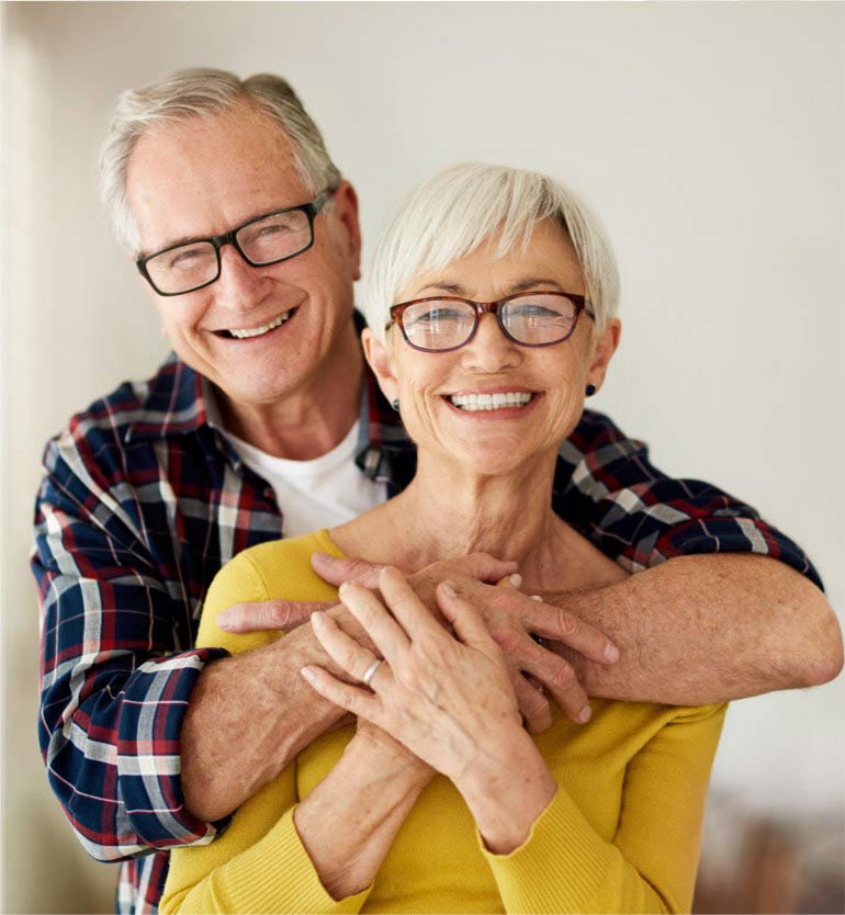 senior-couple Smiling senior couple, the man hugging the woman from behind in a brightly lit room.