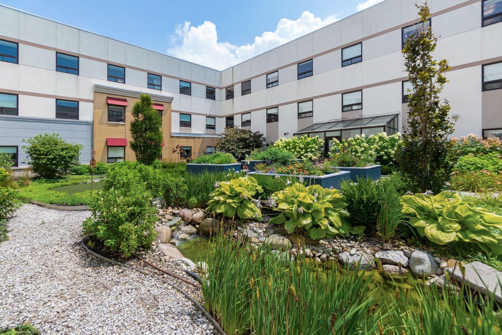 Outdoor garden area at a senior living community in Lewis Center, Ohio with lush greenery and walkway.