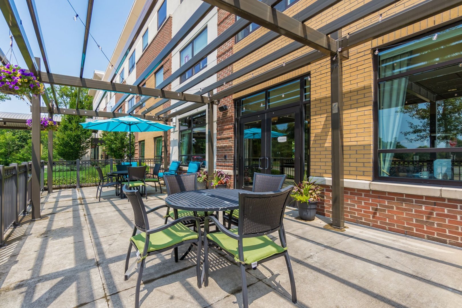 Outdoor patio area with seating and blue umbrellas at a senior living community in Lewis Center, OH.
