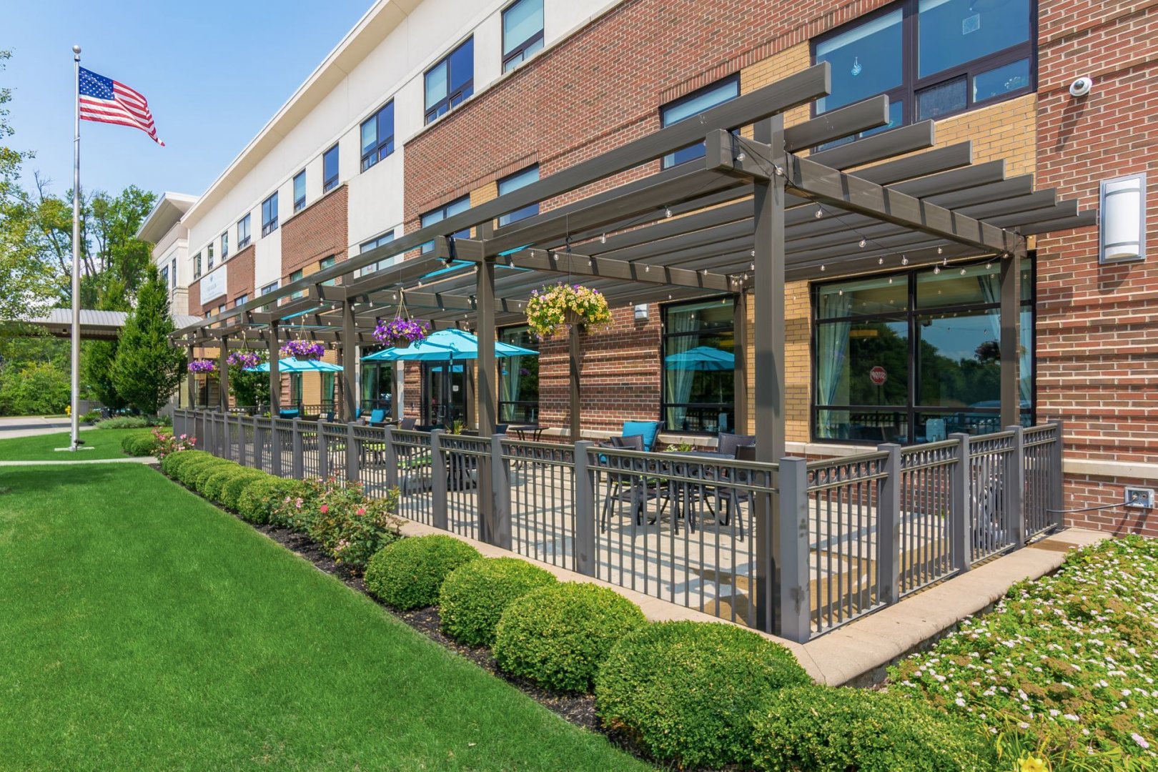 Outdoor seating area with pergolas and hanging flower baskets at senior living community.