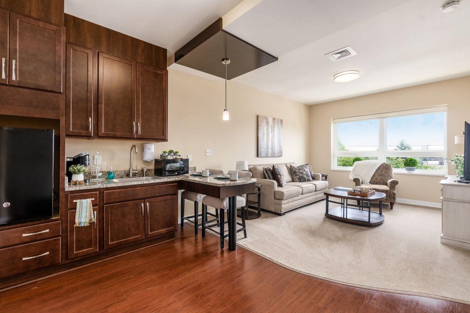 Comfortable living space with a kitchenette and seating area in a senior living community unit.