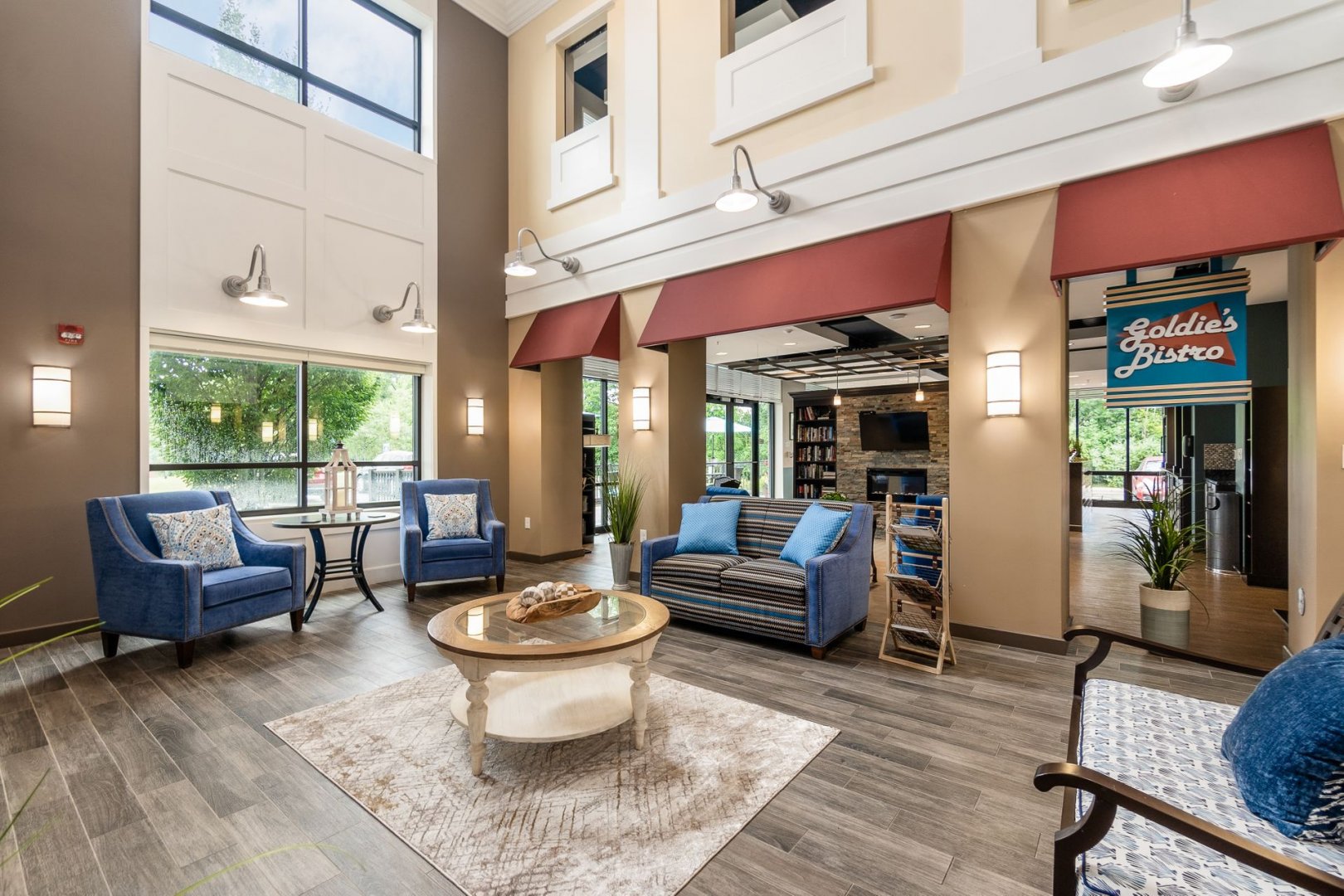Stylish common area with blue chairs, a coffee table, large windows, and a bistro sign.