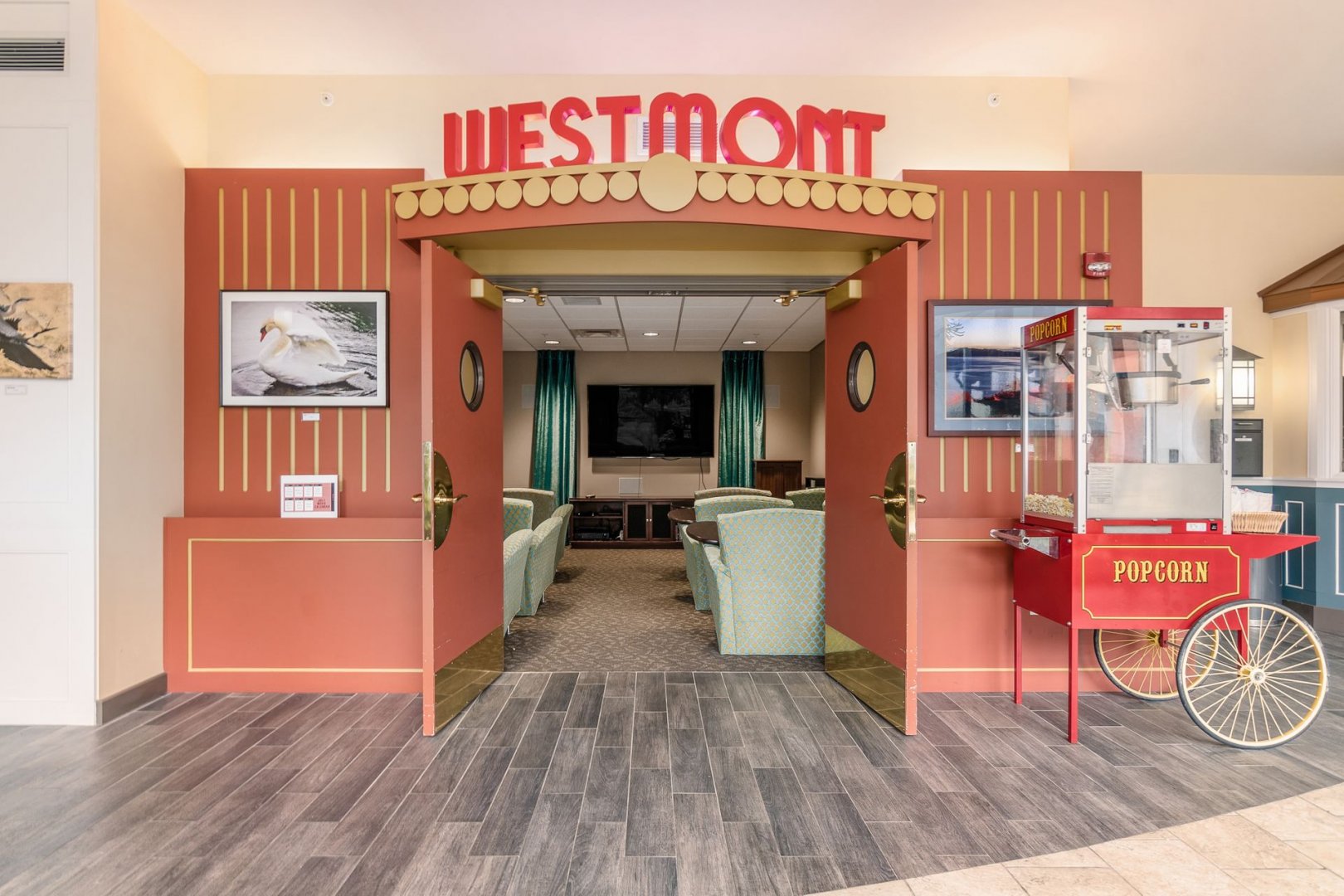 Theater room entrance with red doors and popcorn machine at a senior living community.