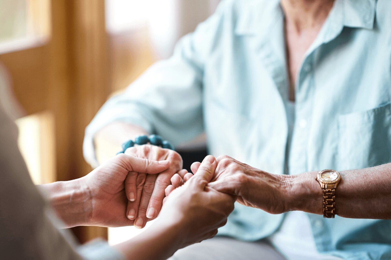 senior-woman-holding-hands-close-up senior woman holds hands with another