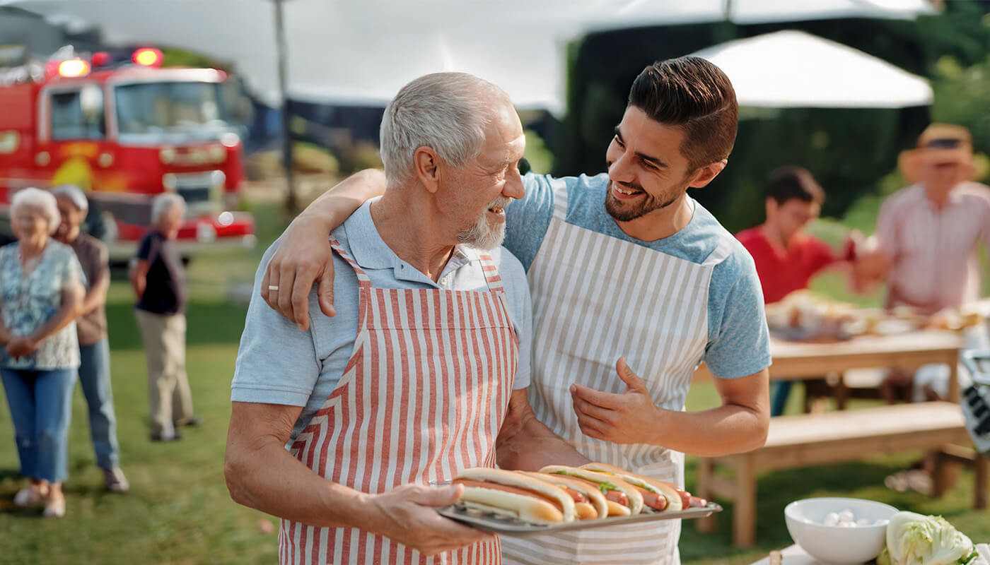 Senior man and young man smile at cookout